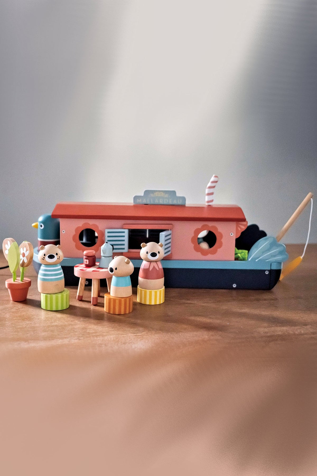 Colorful wooden toy set featuring a charming canal boat named Mallardeau, accompanied by three otter figures. The boat includes details like windows, a fishing rod, and playful accessories.