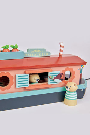 Colorful wooden canal boat named Mallardeau, featuring a cozy cabin with a bear peeking out and a second bear standing nearby. It showcases a sustainable design ideal for imaginative play.