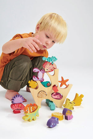 A child plays with a colorful wooden stacking coral reef toy featuring various sea creatures and a natural wood base.