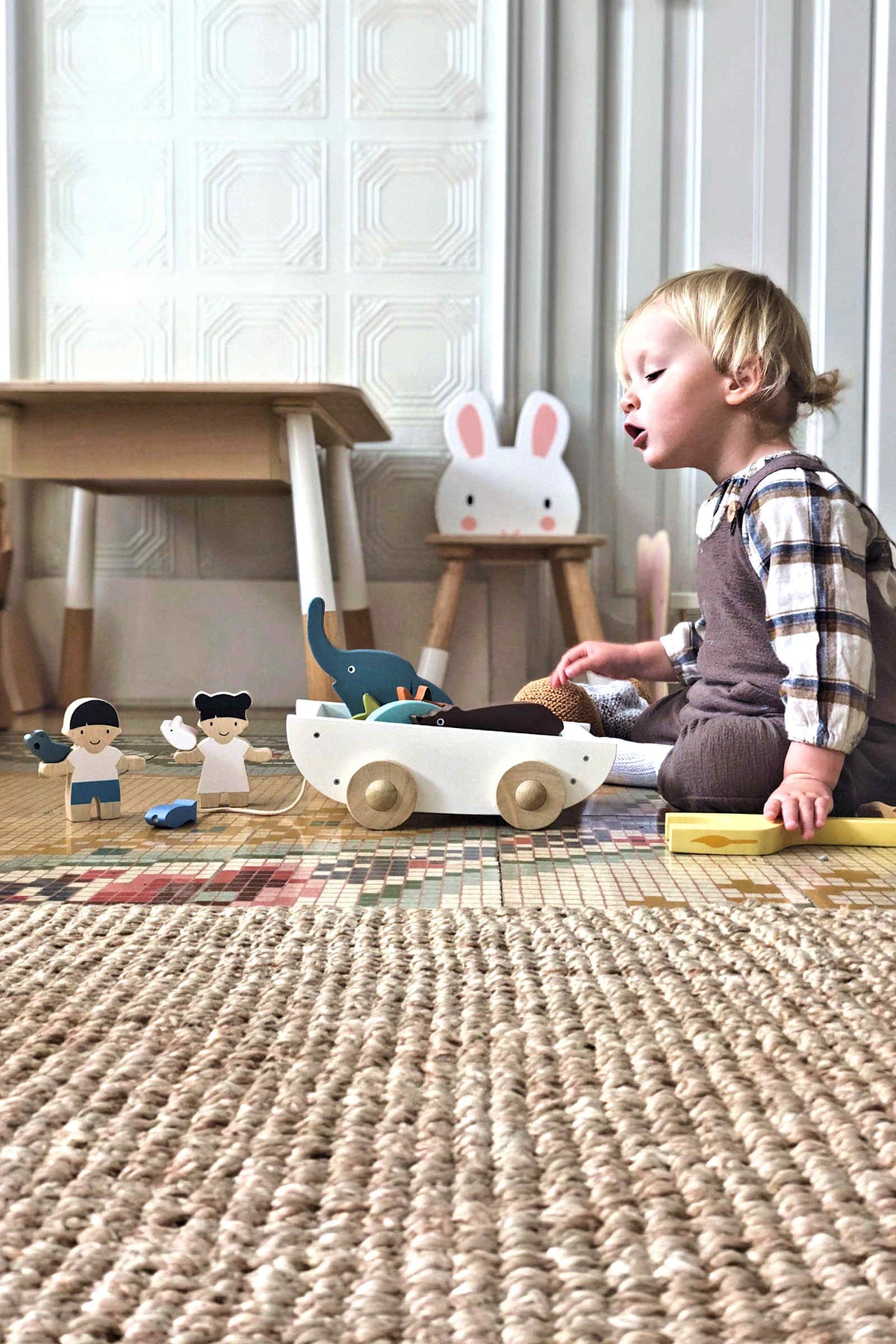A child plays with the Tender Leaf wooden toy, The Friend Ship, featuring colorful animal figures on a textured rug.