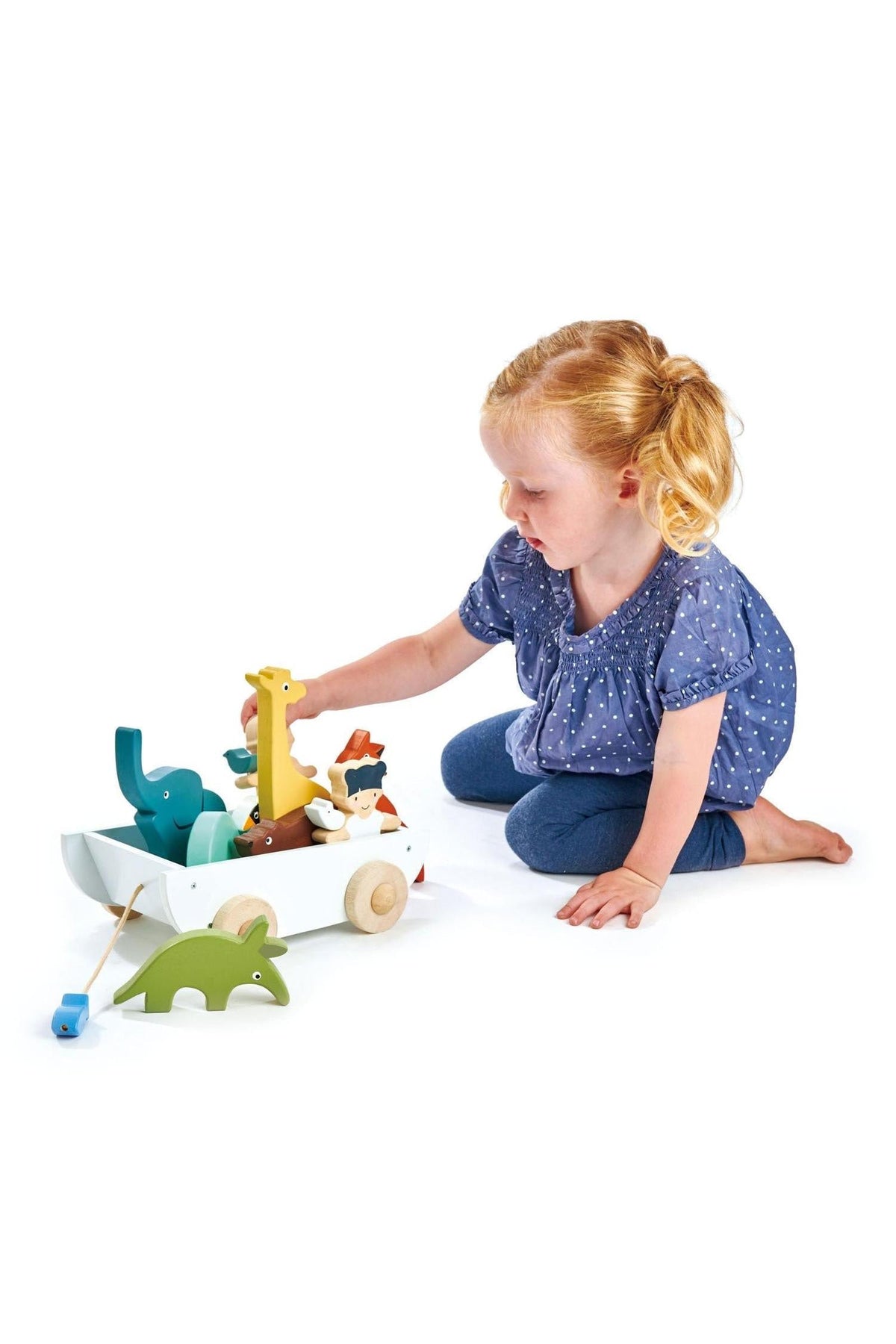 A child plays with a colorful wooden toy set featuring various animal figures in a pull-along wagon.