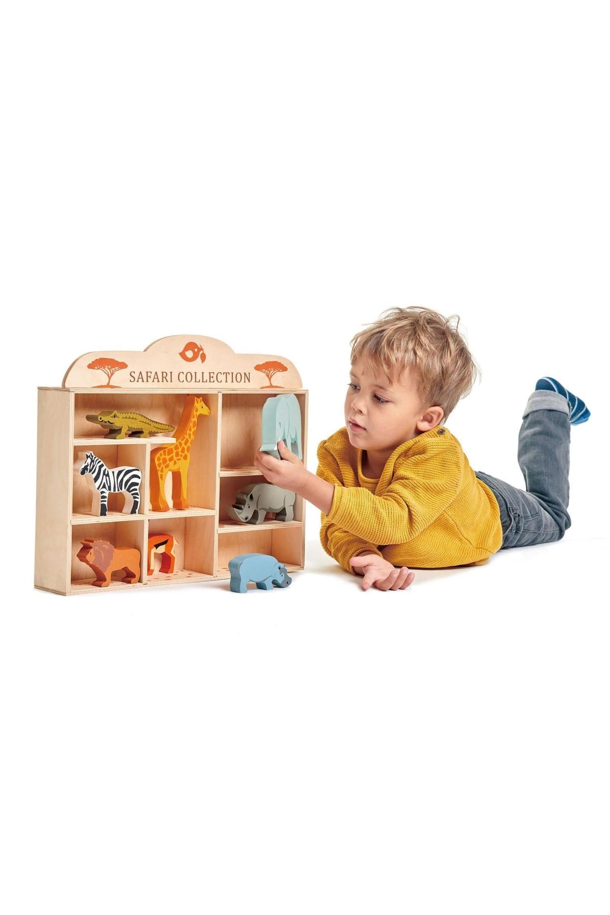 A young boy in a yellow sweater plays with the Tender Leaf Wooden Toys Safari Collection, featuring colorful animal figures.