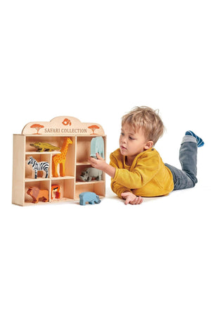 A young boy in a yellow sweater plays with the Tender Leaf Wooden Toys Safari Collection, featuring colorful animal figures.