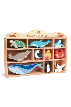 A wooden display shelf featuring colorful coastal creature toys, including a turtle, dolphin, seal, and more, from Tender Leaf.