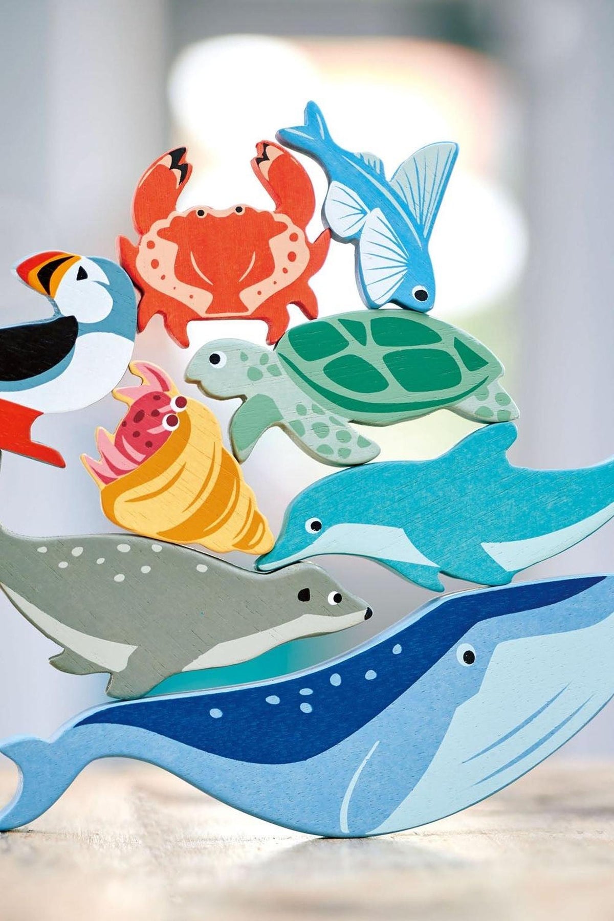 A colorful wooden toy display features various coastal creatures, including a whale, dolphin, sea turtle, and crab, highlighting sustainable craftsmanship.