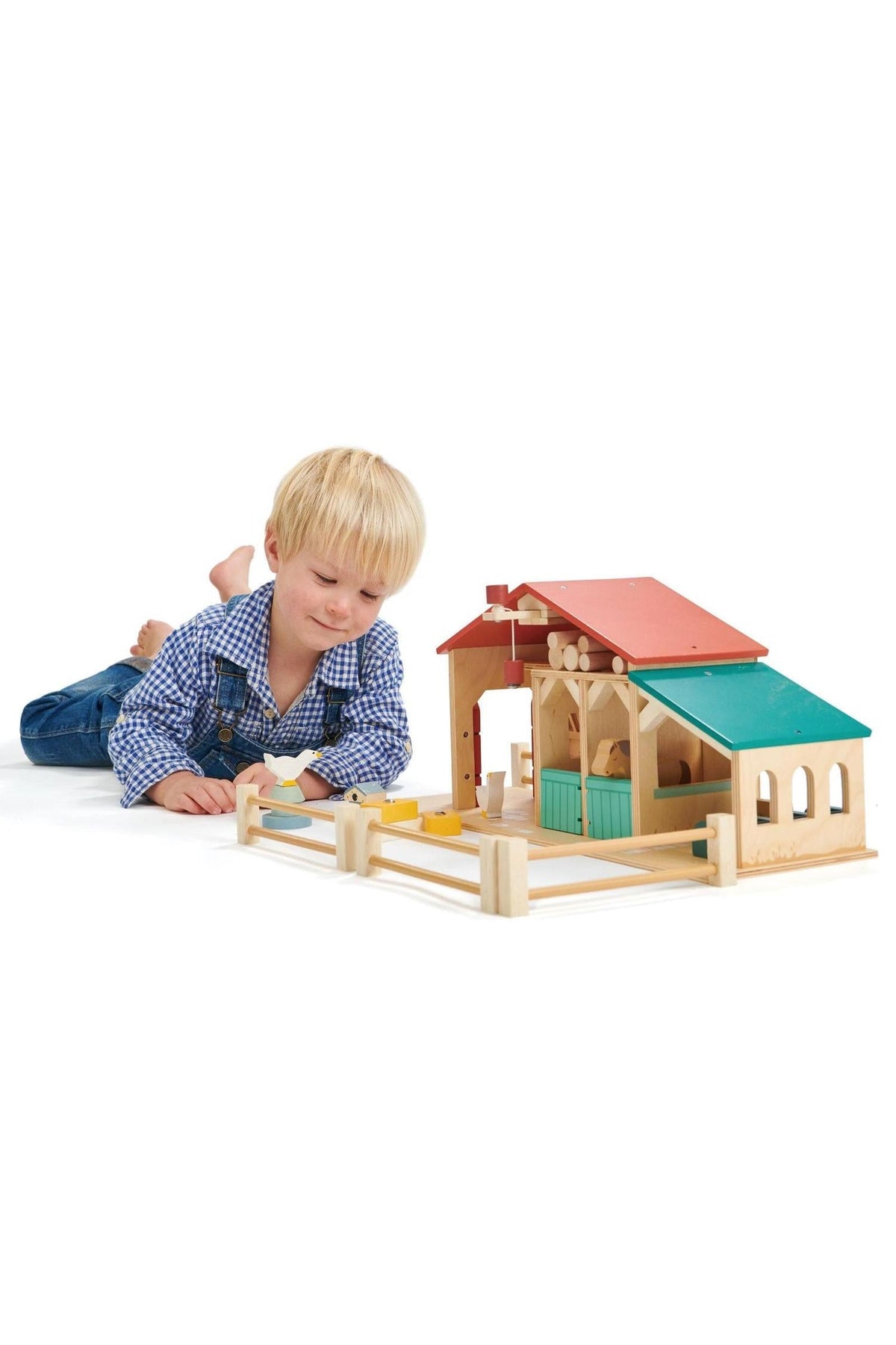 A child plays with a colorful wooden farm toy set, featuring a barn and stables, promoting imaginative play and fine.