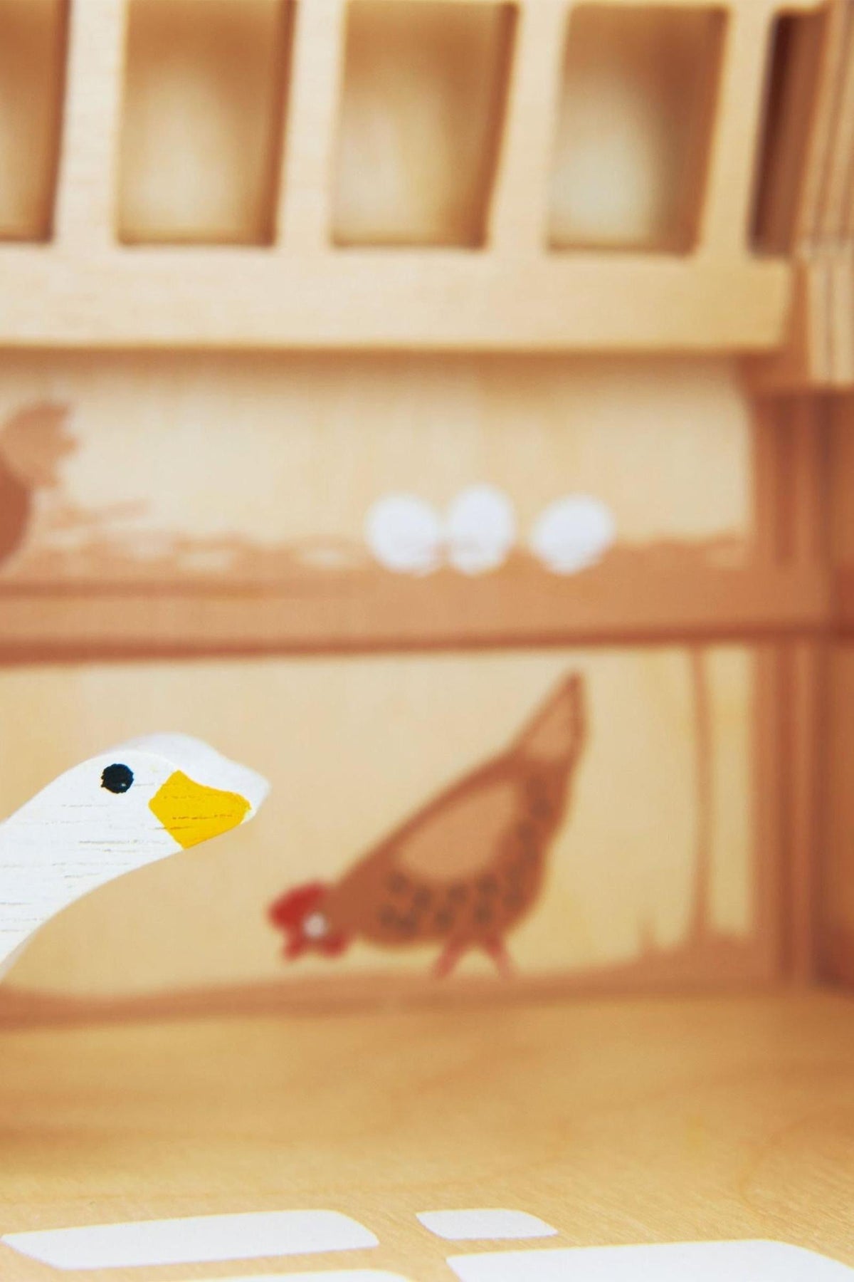 A close-up of a wooden toy farm interior featuring a painted goose and hen, highlighting eco-friendly materials and craftsmanship.