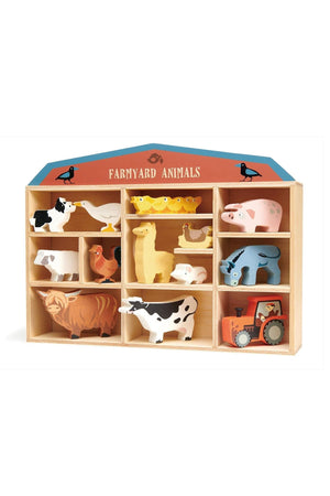 A wooden display shelf holds various colorful farmyard animal figures, including a cow, sheep, duck, and tractor. The collection emphasizes sustainable play for children aged three and older.