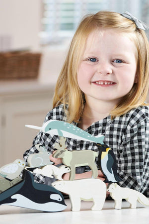 A smiling girl holds a colorful collection of wooden polar animal toys, showcasing their playful designs and eco-friendly materials.