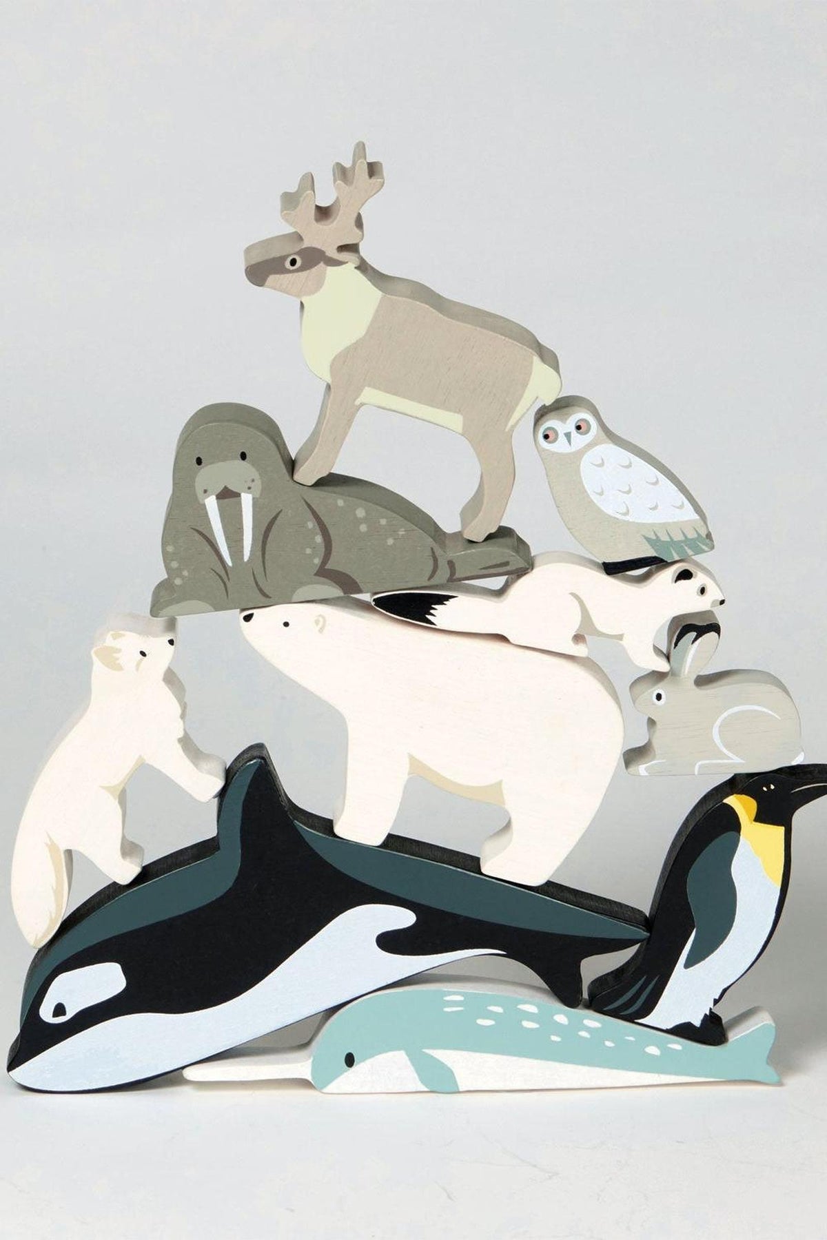 A wooden toy display features various polar animals, including a polar bear, walrus, and penguin, in soft colors.