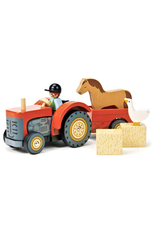A vibrant red wooden tractor with a removable driver, featuring a horse and duck on a trailer, alongside hay bales.