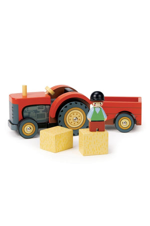 A vibrant red wooden farmyard tractor with a removable trailer, accompanied by a farmer figure and yellow building blocks.