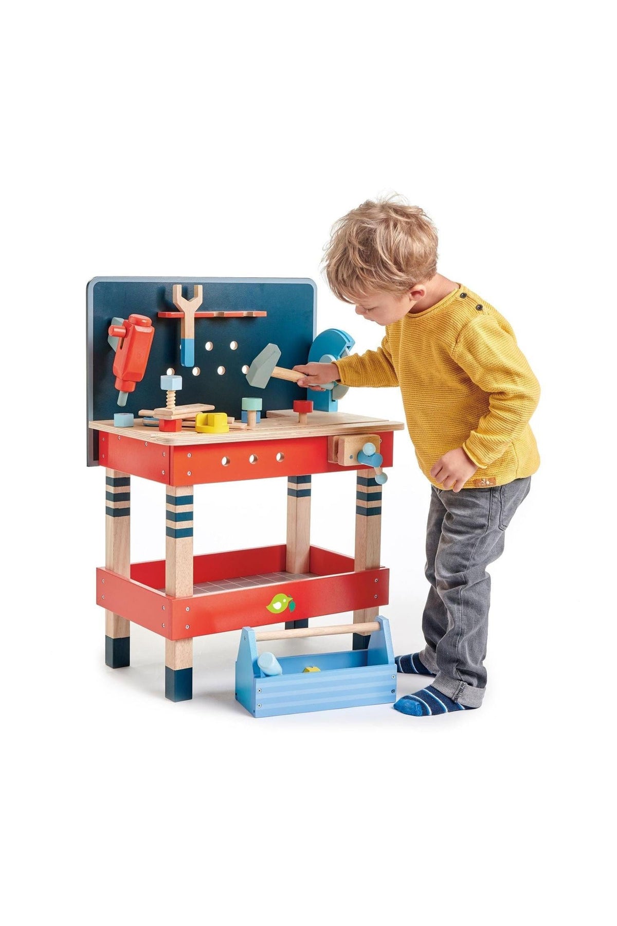 A young child interacts with a colorful wooden tool bench, featuring various tools and a blue toolbox for imaginative play.