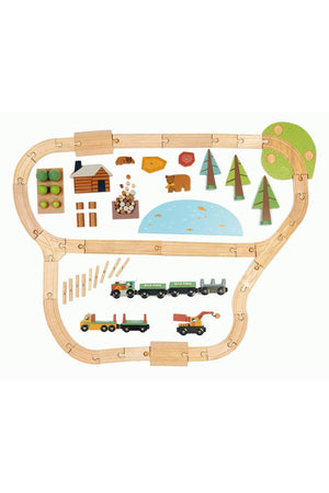 A colorful wooden train set layout features a curved track, various trees, logs, and two vehicles, including a logging truck and a loader.