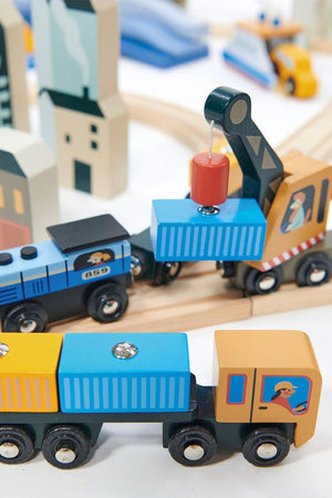 Colorful wooden train cars are connected on a track, featuring a blue crane lifting a cargo container. The vibrant design reflects a playful, imaginative setting ideal for children.