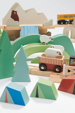 Colorful wooden toy train set featuring green hills, trees, and a variety of geometric shapes. Includes sheep in a cart and a bear in the background, promoting imaginative play.