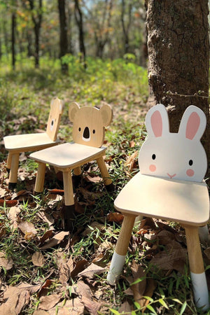 Three toddler chairs, featuring a rabbit and koala design, are placed on grass under a tree, showcasing natural wood materials.