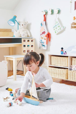 A young child plays with a wooden sailing boat on a soft carpet in a bright, cozy room filled with.