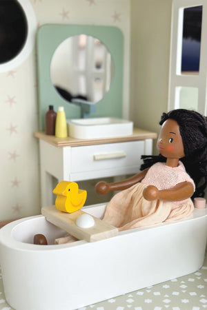 A wooden doll in a bathtub with a yellow duck and bathroom furnishings, featuring eco-conscious materials.