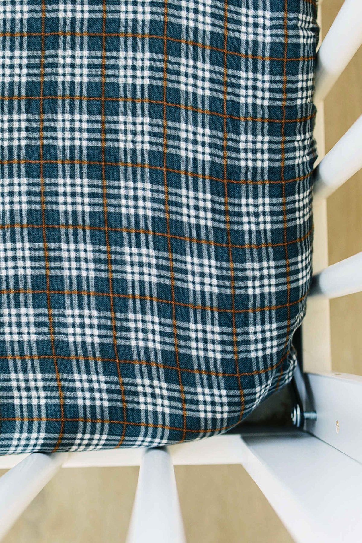 Navy plaid muslin crib sheet on a white crib, featuring a soft, breathable 100% cotton fabric.