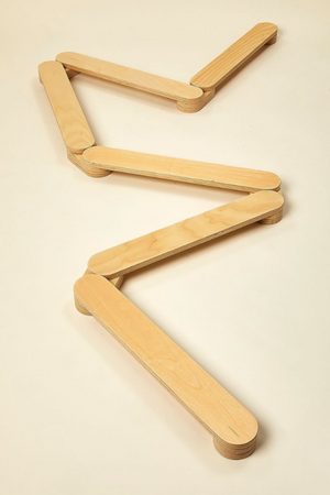 A zigzag balance beam made from smooth, light-colored wood lies flat against a neutral background. This sturdy, eco-friendly design encourages active play and coordination for children.
