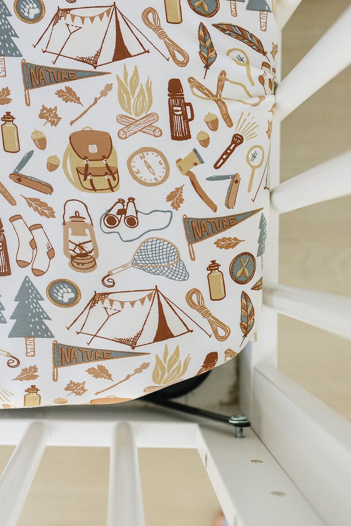 Crib sheet with camping-themed illustrations, including tents and compasses, made from soft bamboo fabric in a crib setting.