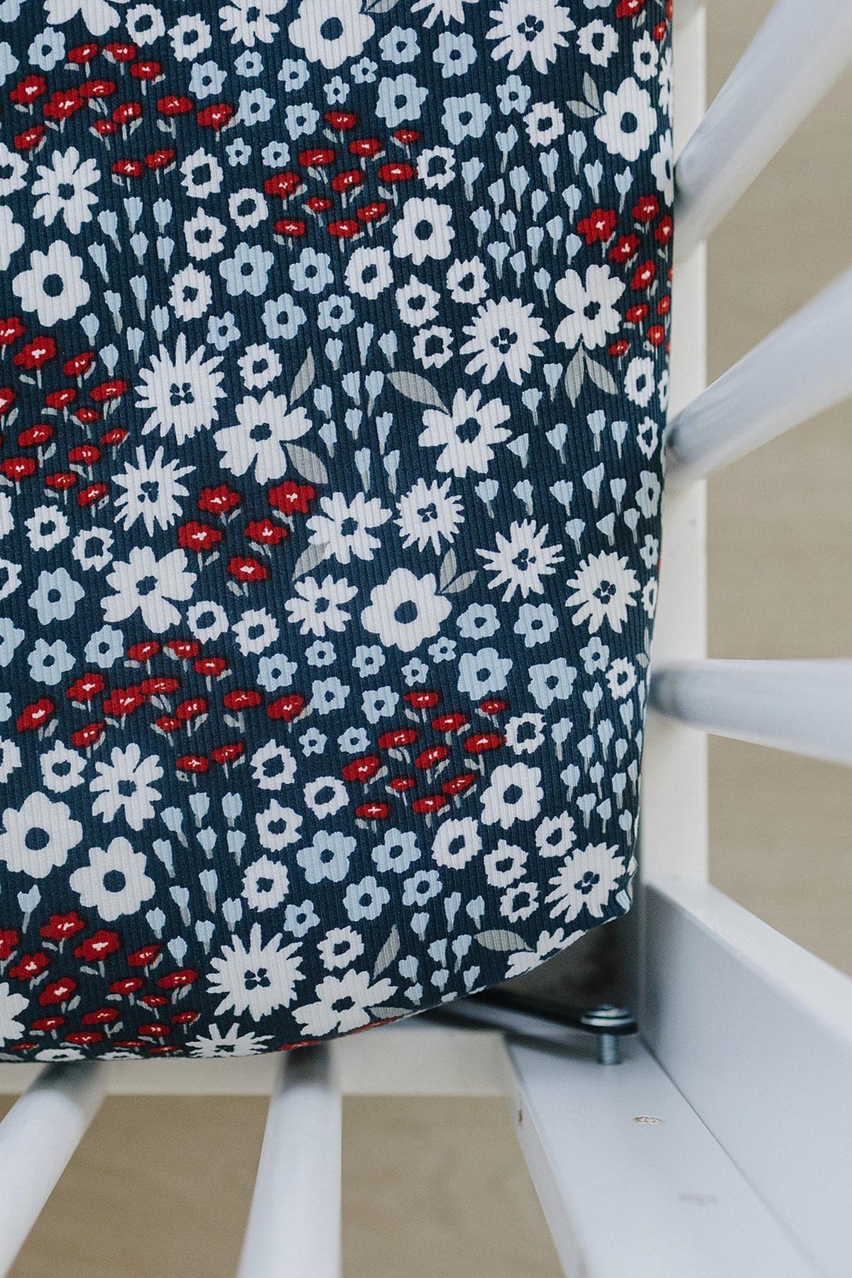 Floral crib sheet with navy, white, and red pattern on a white crib. Made from soft, breathable bamboo fabric.