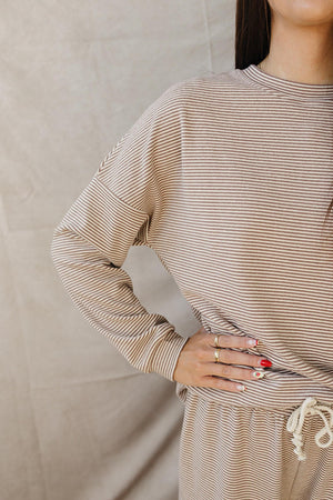 A close-up of a woman’s striped loungewear set in soft, breathable cotton, featuring long sleeves and a relaxed fit.