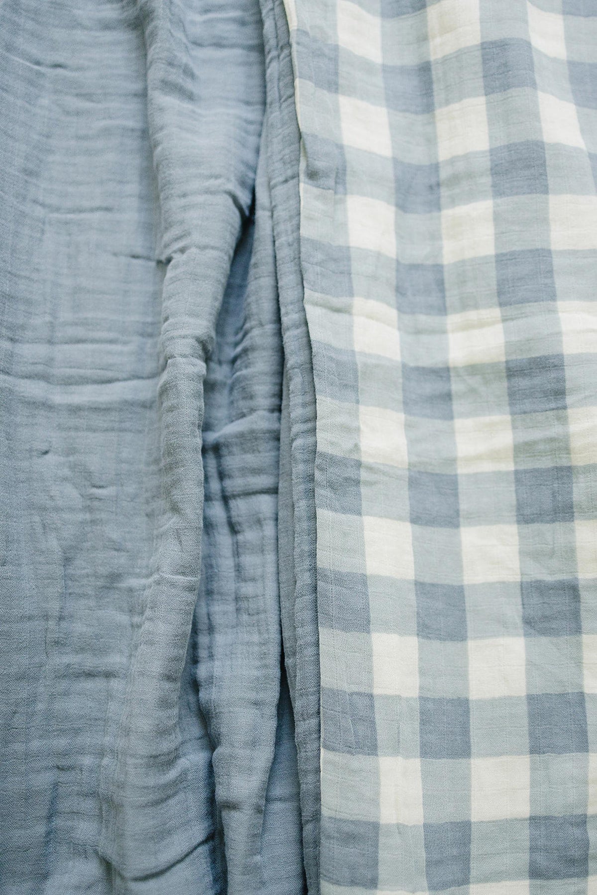 Dusty blue gingham quilt with a soft, textured muslin fabric, showcasing a checkered pattern in a close-up view.