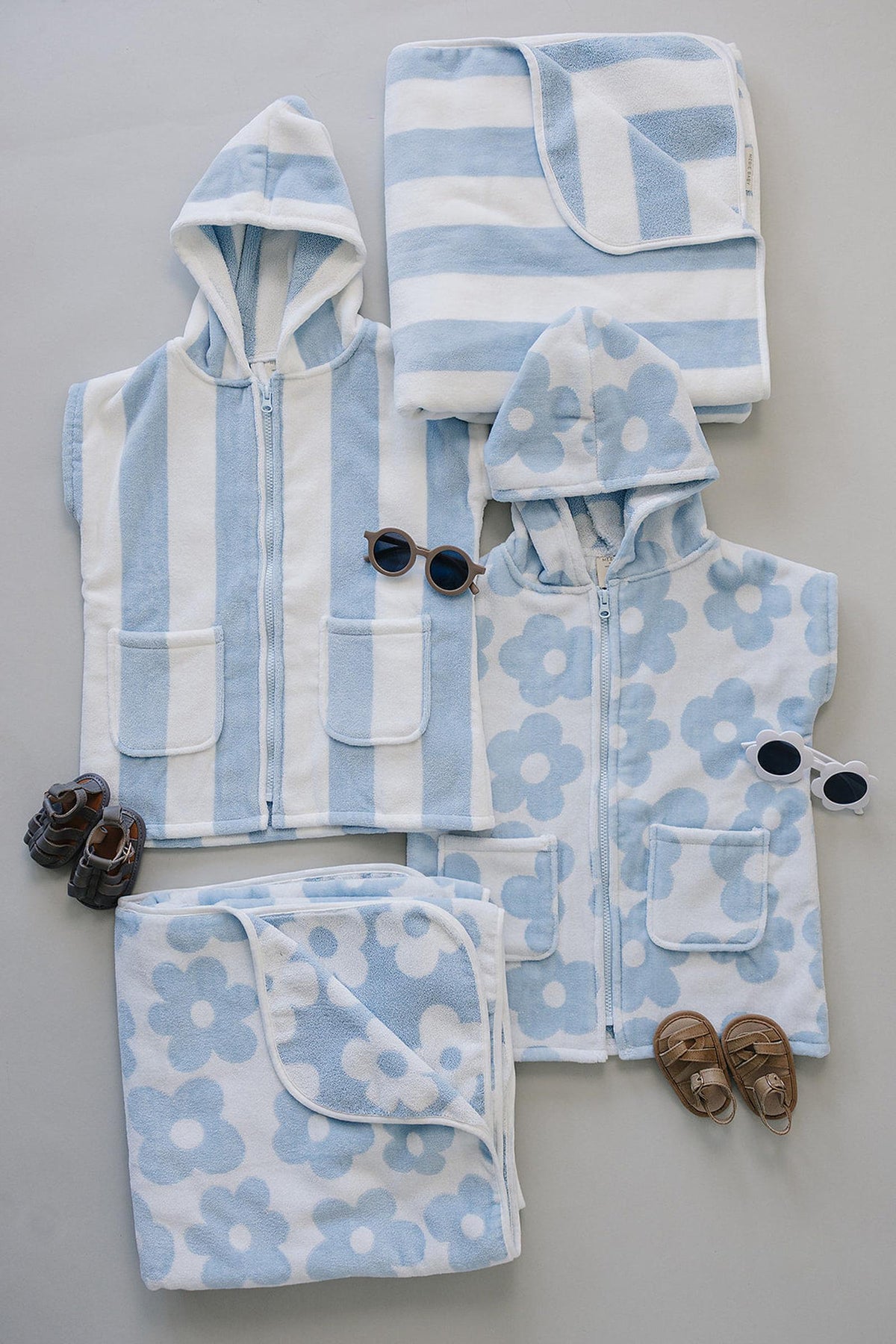 A collection of light blue and white beach towels and hooded ponchos made from soft, absorbent fabric.