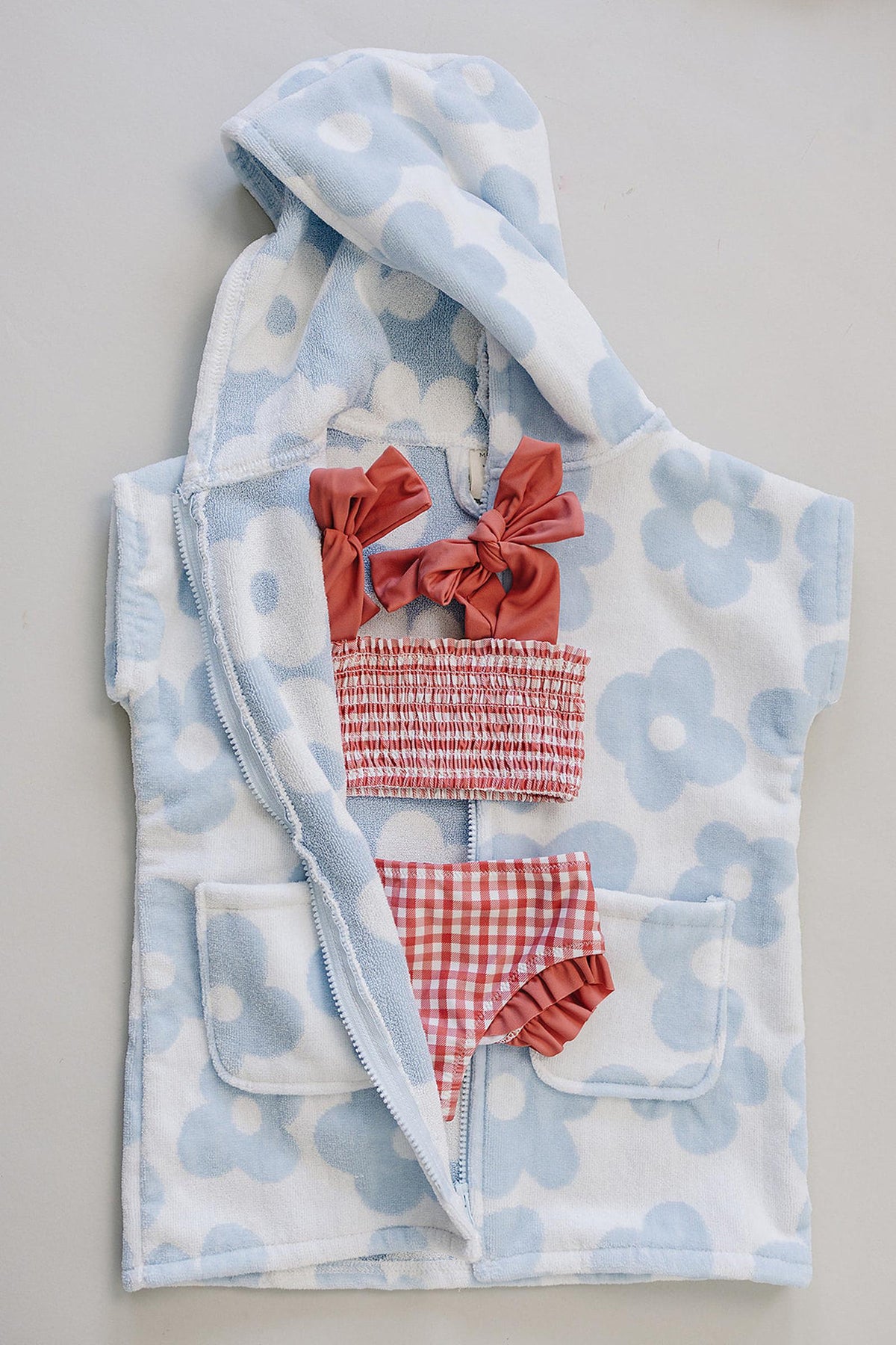 Light blue and white floral zip-up beach poncho made from soft organic cotton, featuring a cozy hood and two front pockets.