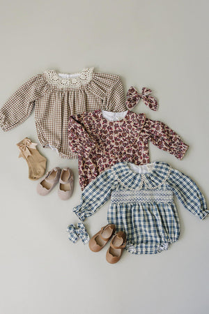Three childrens outfits are displayed on a light gray background, featuring a plaid romper, floral blouse, and checkered bubble romper, paired with matching shoes and accessories.