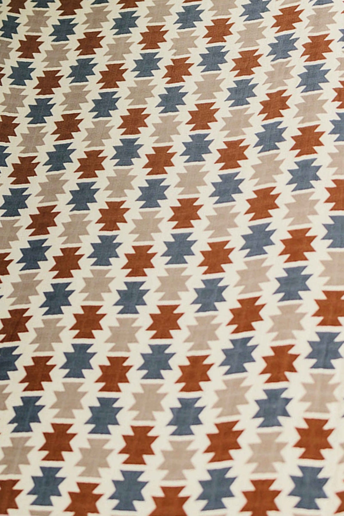 Aztec-patterned fabric with brown, blue, and beige geometric shapes on a white background.
