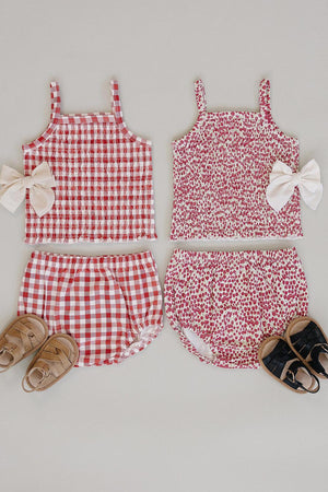 Two baby girl outfits displayed flat: a red gingham top and bloomer set, and a floral print top with matching.
