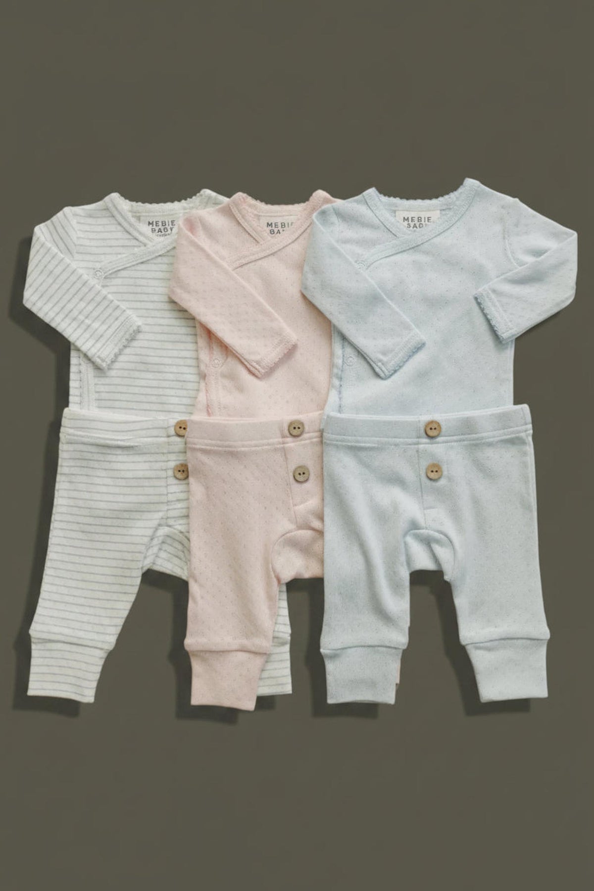 A set of four baby layette outfits in soft, breathable cotton, featuring pastel colors: light blue, pink,.