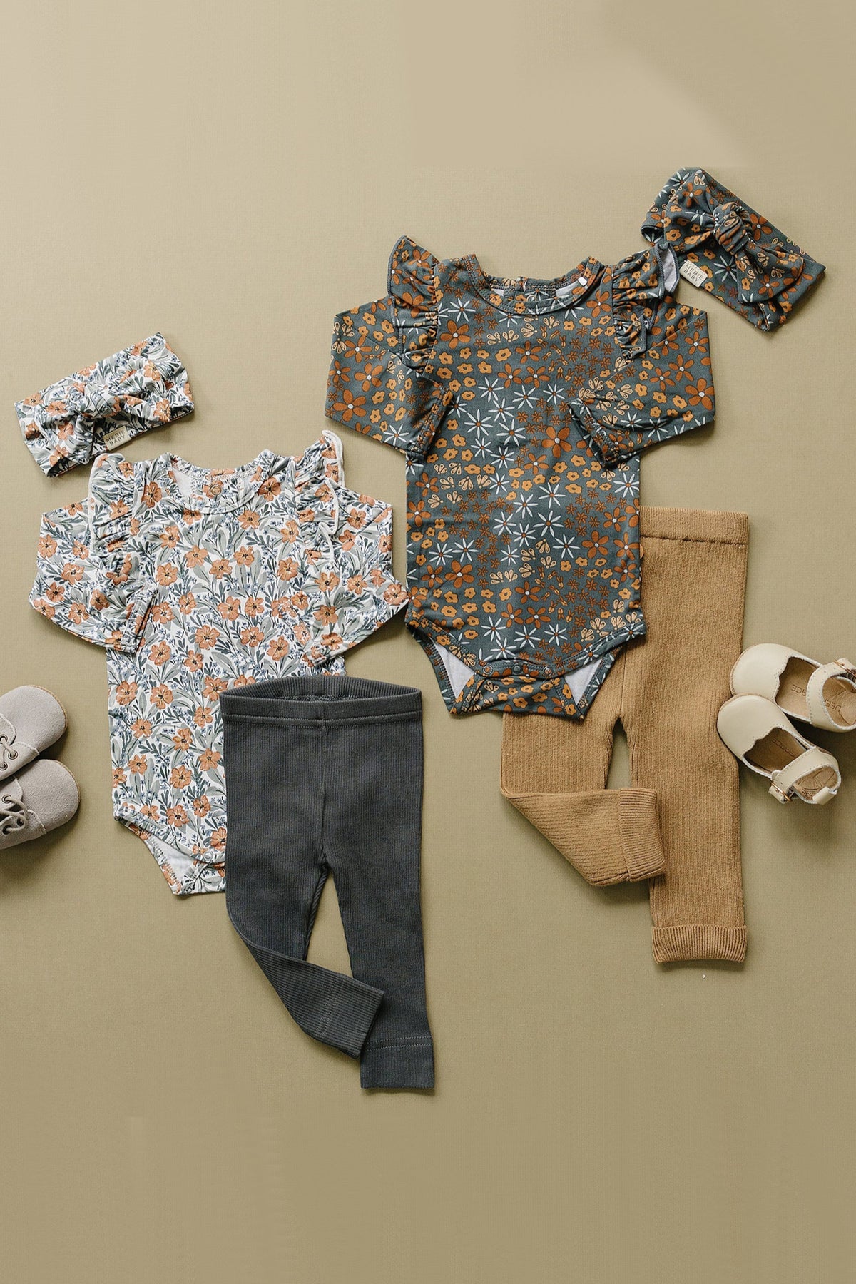 Two floral baby bodysuits with ruffle sleeves, matching headbands, pants, and shoes displayed on a beige background.