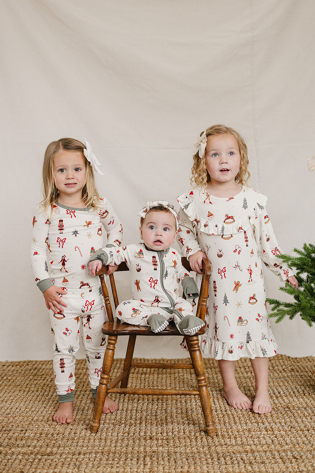 Three children are styled in festive holiday pajamas featuring cheerful prints on soft, organic bamboo fabric. They stand together in front of a neutral backdrop, exuding a cozy, cheerful vibe.
