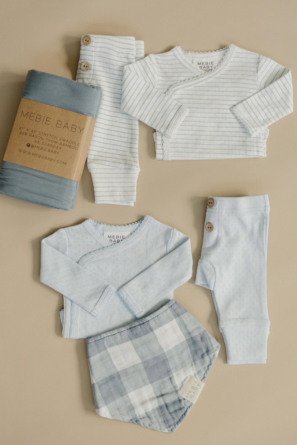 Mebie Babys blue stripe pointelle layette set features soft, breathable cotton outfits, including a long-sleeve top, pants, and a plaid bib, ideal for newborns.