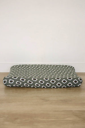 A soft, muslin changing pad cover features a Southwest Aztec pattern in green, black, and white. Its breathable fabric is ideal for creating a cozy changing surface.