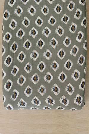 Soft muslin changing pad cover featuring a Southwest Aztec pattern in earthy tones of green, white, and navy. Ideal for adding a cozy, modern touch to any nursery setting.