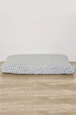 A muslin changing pad cover features a blue floral pattern on a white background, showcasing soft, breathable cotton fabric.