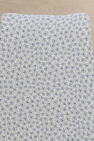 A close-up view of a muslin changing pad cover featuring a delicate blue floral pattern on a light background.