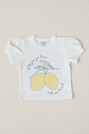 White cotton short-sleeve t-shirt featuring a playful lemon graphic and text that reads, If life gives you lemons, make some lemonade. Ideal for young girls, combining charm and comfort.