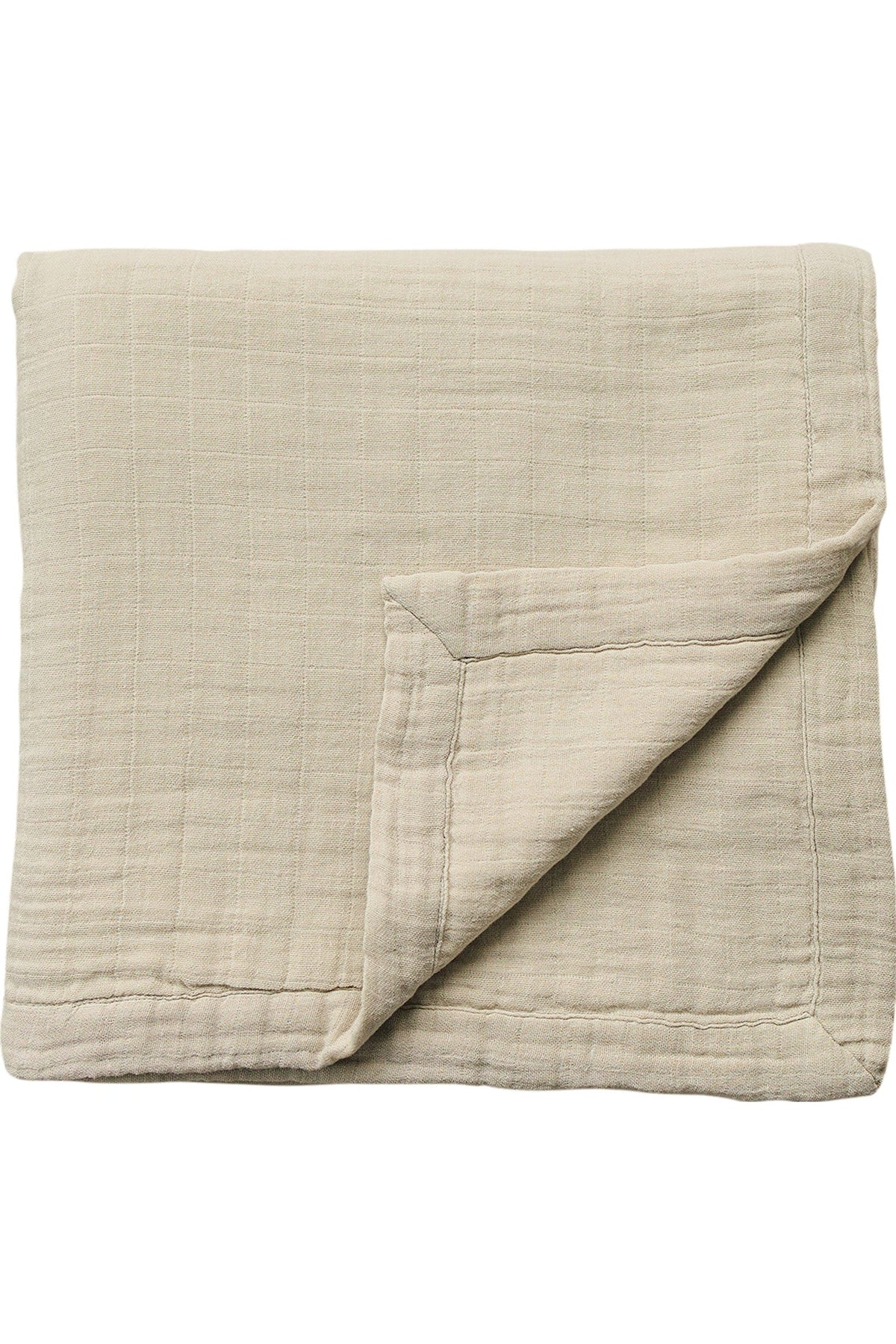 A folded oatmeal-colored muslin quilt with a visible corner flap, showcasing its soft, textured cotton material.