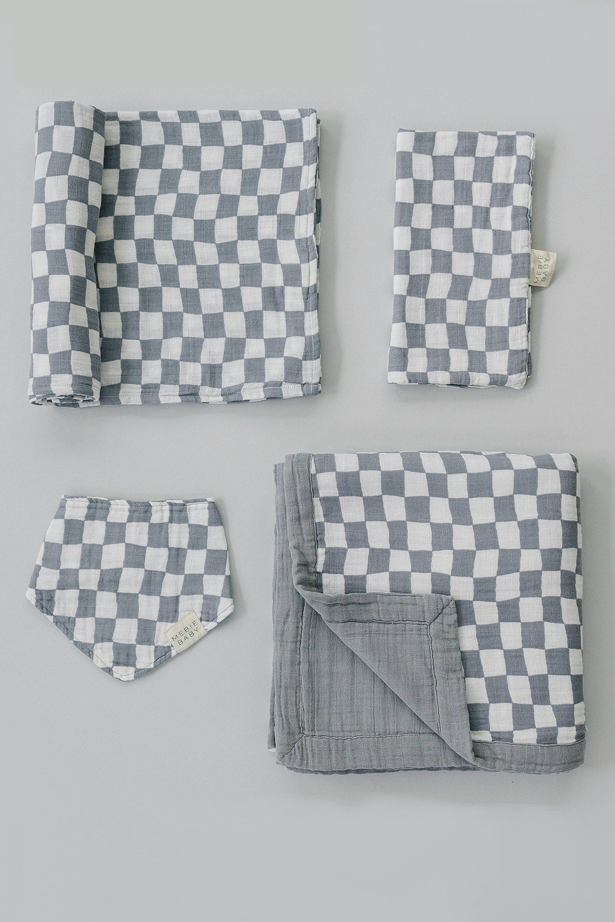 Gray and white checkered muslin cloth set includes a crib sheet, bib, and two folded pieces.