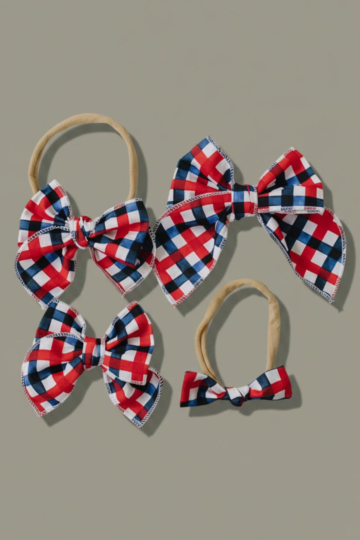 A set of four plaid hair bows in red, white, and blue, made from cotton fabric, displayed on a light gray background.