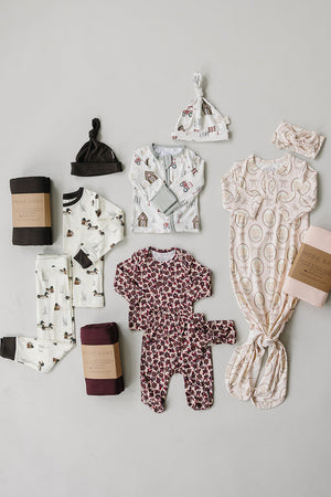 A collection of baby essentials, including ribbed bamboo sleepwear and swaddles in soft colors and playful patterns, arranged neatly on a light background. Ideal for delicate skin and everyday use.