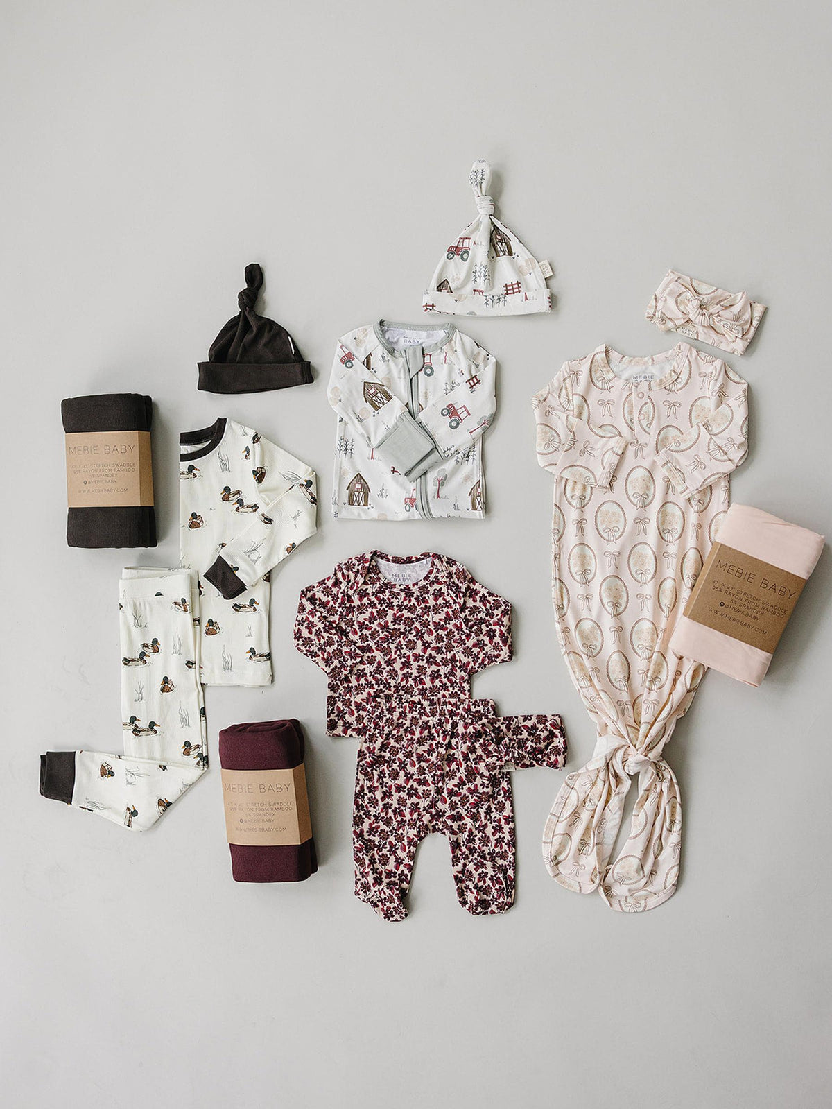 A flat lay displays a variety of baby and kids sleepwear, featuring ribbed bamboo fabric in soft colors and playful patterns, including pajamas, a sleep sack, and matching accessories.