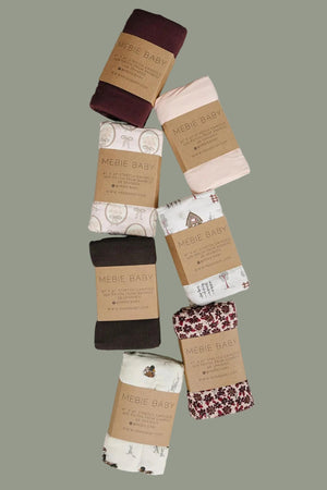 A collection of seven rolled fabric swaddles from Mebie Baby, featuring various pastel colors and playful patterns, displayed on a light surface. These soft, breathable swaddles are ideal for newborns.