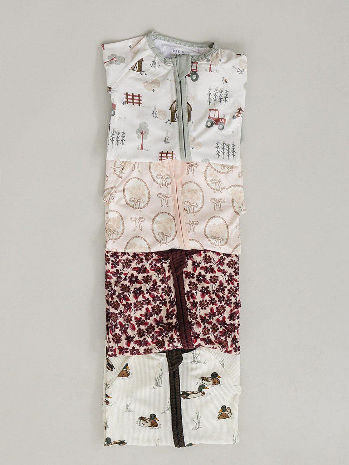 A collection of bamboo zipper pajamas in soft colors, featuring playful patterns of trees, animals, and flowers. The two-way zipper allows for easy diaper changes, ideal for infants.